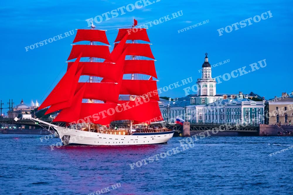 На фотографии изображен корабль с алыми парусами, плывущий по Неве в Санкт-Петербурге на фоне здания Кунсткамеры. Праздник Алые Паруса отмечается в честь выпускников школ и является ярким событием города. Летний вечер и голубое небо подчеркивают красоту этого праздника. Здание Кунсткамеры добавляет исторического и культурного контекста к сцене.